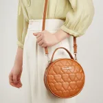 Petit sac rond en cuir marron porté par une femme